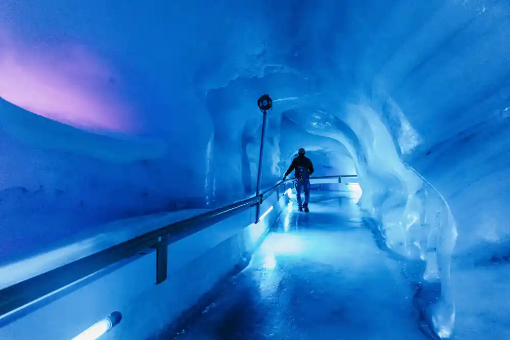 The blue ice tunnel of the glacier cave with a figure far down it