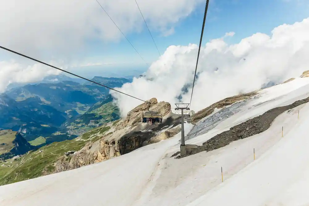 Cable car wires running up a snow slope into cloud near the top station
