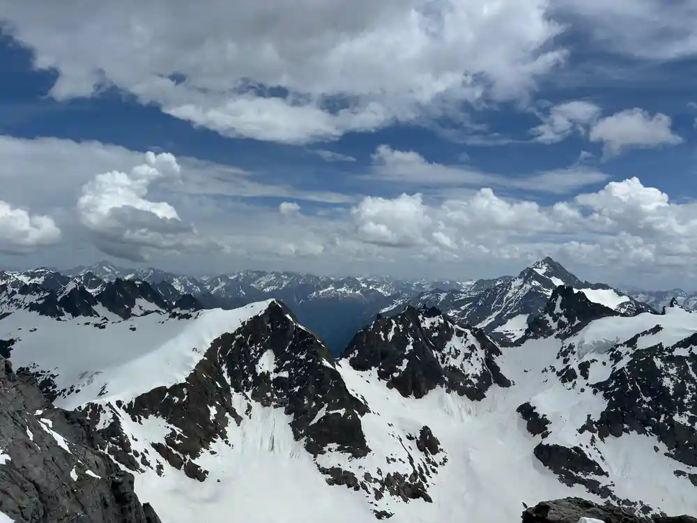 A dark rock ridge streaked with snow under cloud