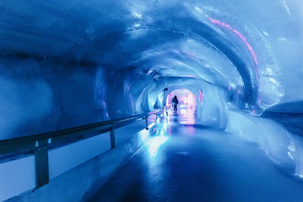 The full length of the glacier cave tunnel lit blue and violet