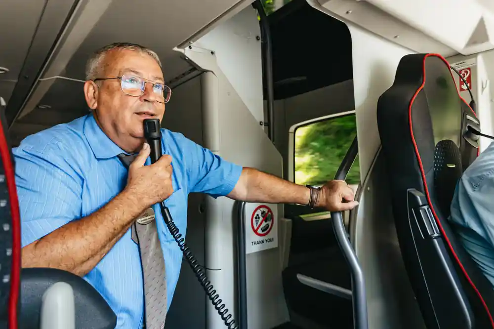 The guide speaking into a microphone at the front of the coach