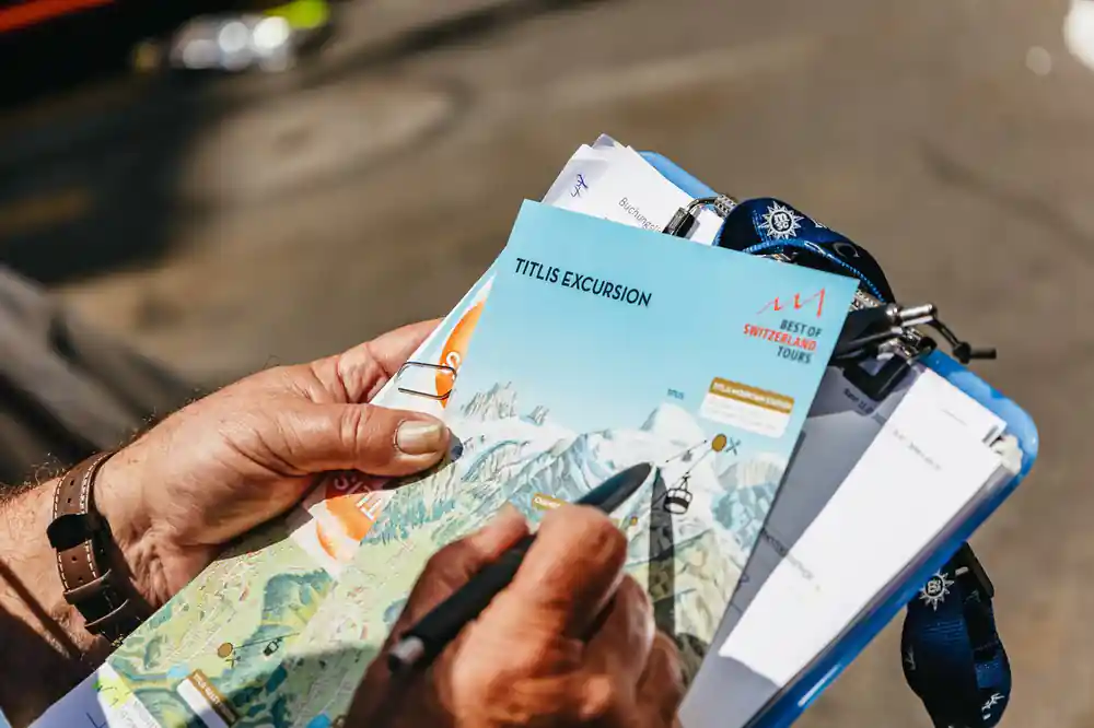 A hand holding a Titlis excursion ticket wallet and a map