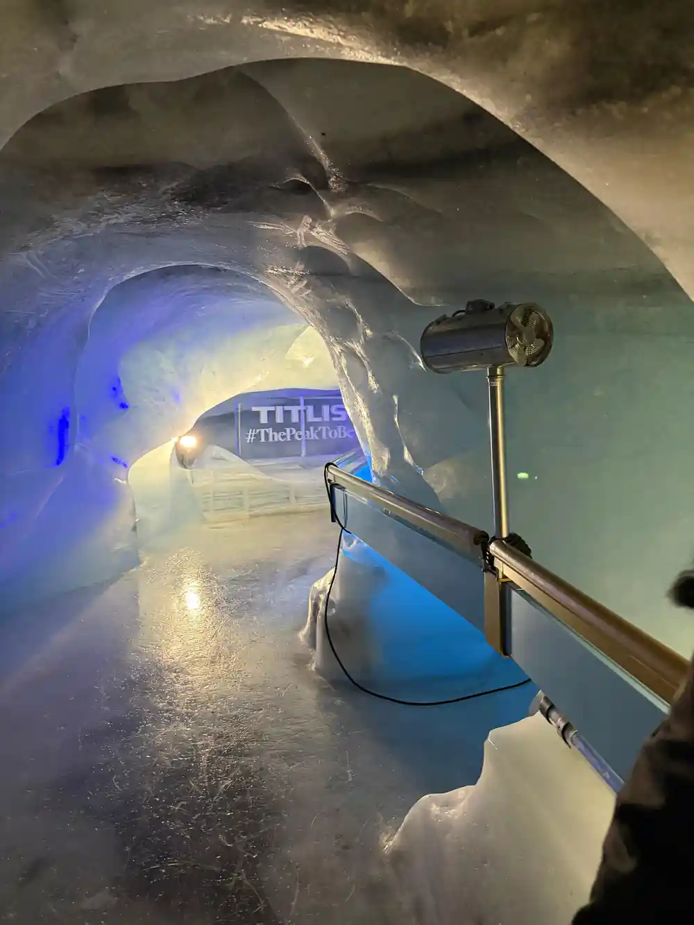 A lit alcove inside the glacier cave with the Titlis name on the ice