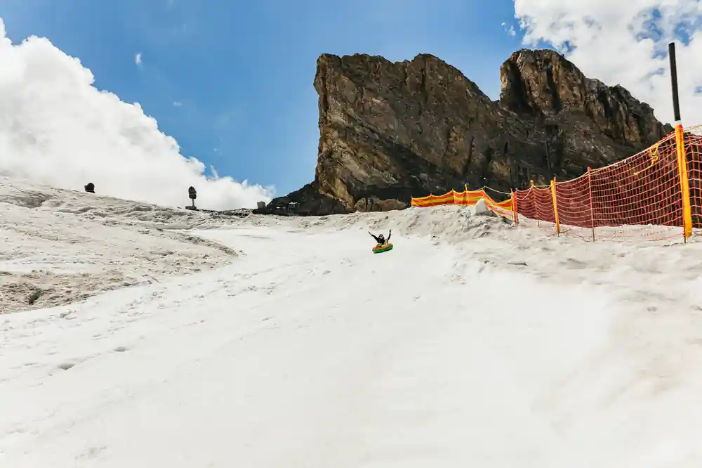 A rider sliding down the tubing slope below the rock ridge