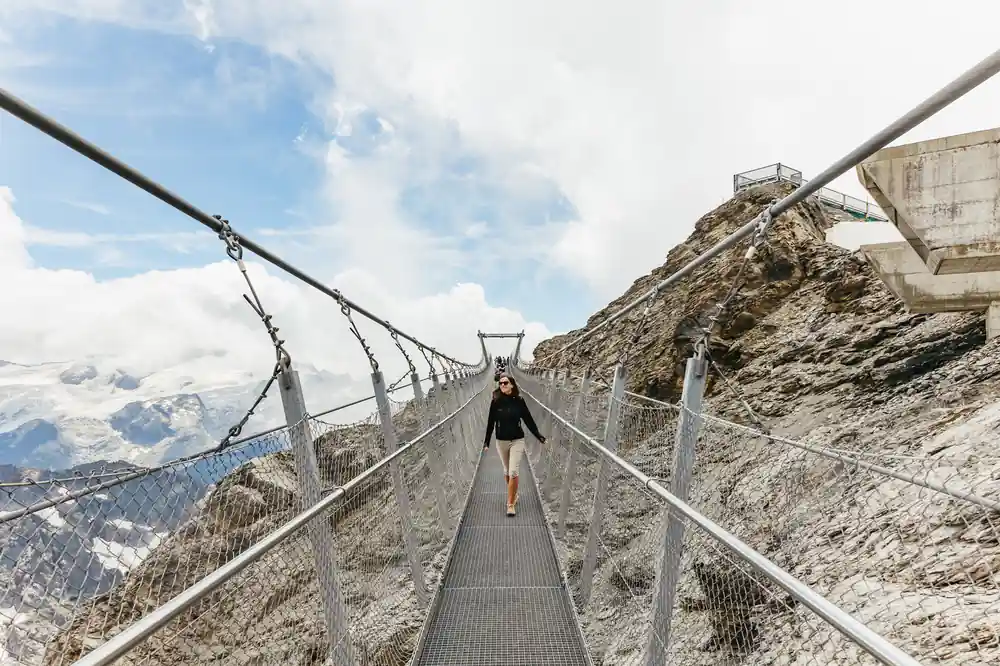 A visitor crossing the Cliff Walk suspension bridge