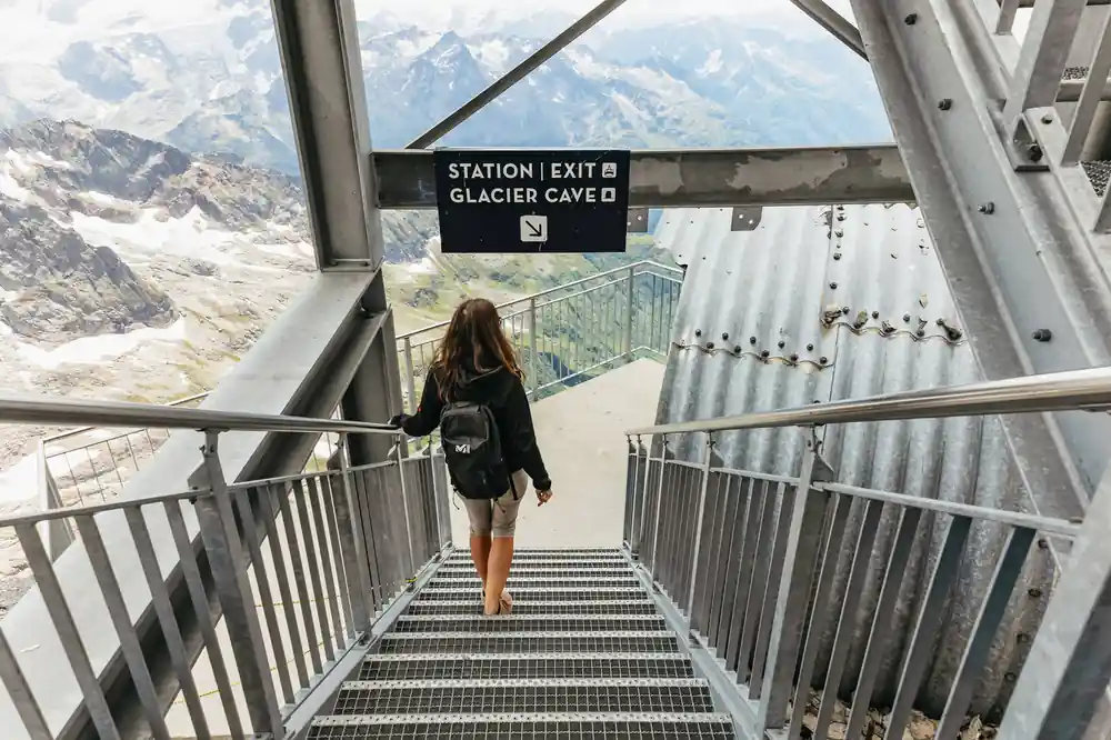 A visitor on the metal stairs beneath a sign for the glacier cave