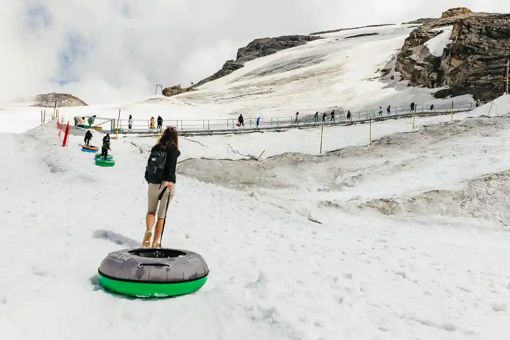 A visitor standing on a snow tube on the glacier run