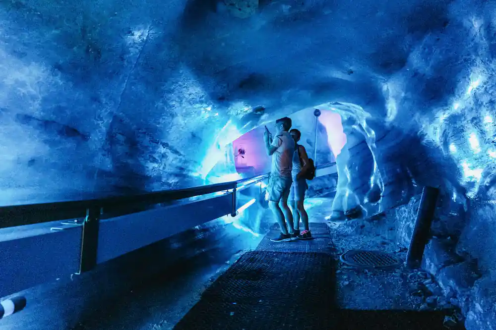 Visitors inside the glacier cave beside a lit ice wall
